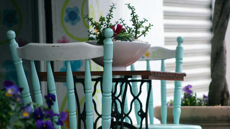 Mid-century wooden armchair painted mint green with hand-stitched cream linen cushions, surrounded by reclaimed wood tools and sandpaper
